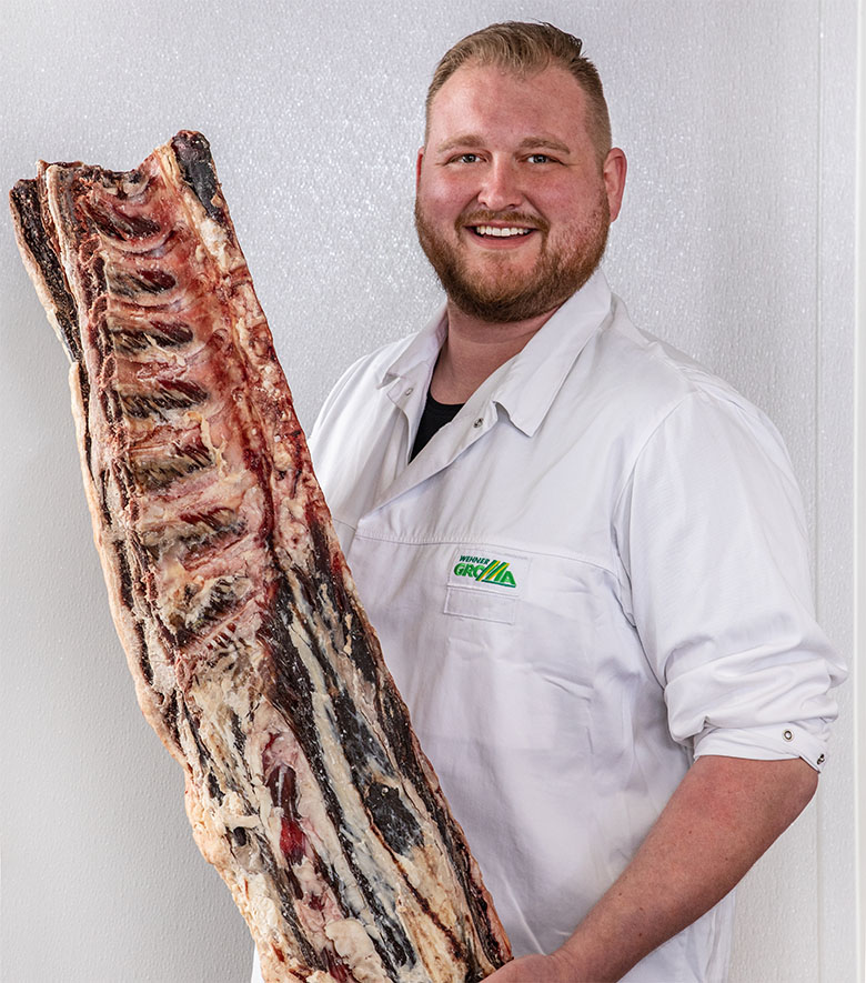 Metzger von GROMA hält ein großes Stück Dry-Aged Fleisch nach oben