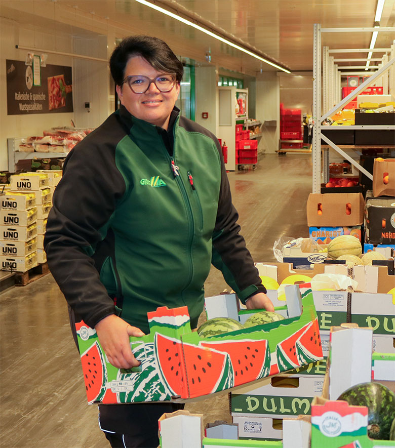 Eine Mitarbeiterin von GROMA räumt Kartons mit Wassermelonen ins Regal Eine Mitarbeiterin von GROMA räumt Kartons mit Wassermelonen ins Regal